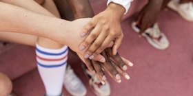Faceless multiracial sport team stacking hands on court. Photo by Monstera Production.