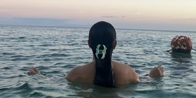 Back of woman with dark hair swimming in the sea
