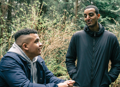 Two men chatting in a forest.png