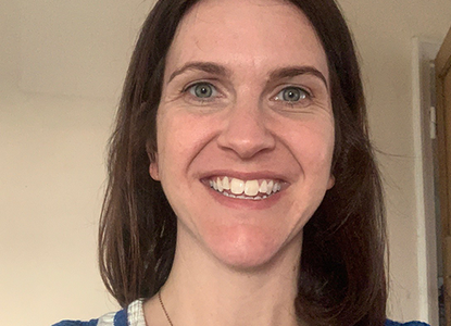 Rosie, a Shout Volunteer with long dark hair and a blue top, smiles at the camera