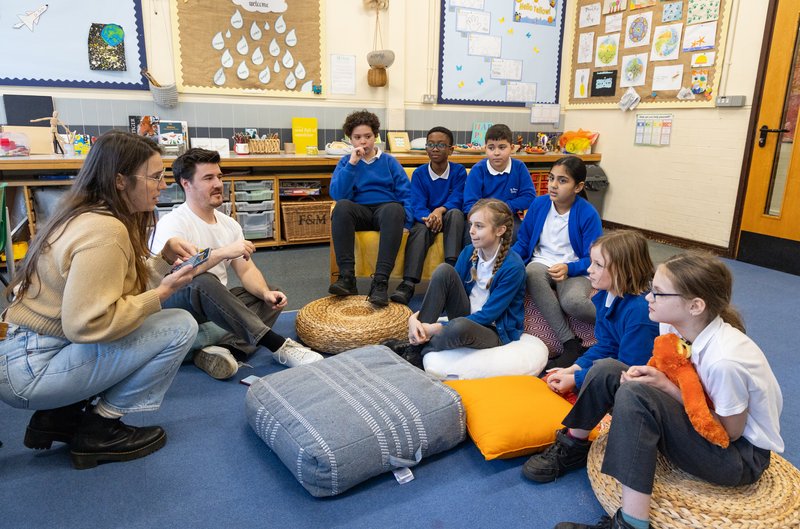A group of young school children sit in a circle talking to each other about mental wellbeing