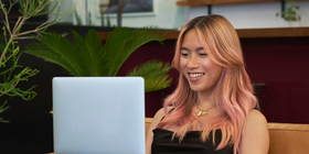 A transfeminine person smiling and using a laptop