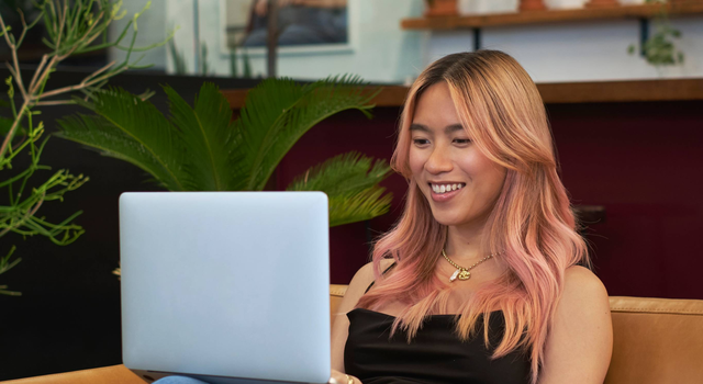 A transfeminine person smiling and using a laptop