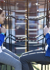 Two girls in school uniform sitting on play equipment